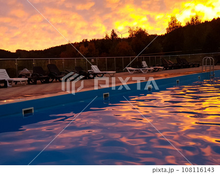 Swimming pool with sun loungers at sunset Swimming pool with sun loungers at sunset 108116143