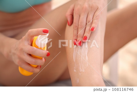 Woman applying sunscreen to her feet closeup 108116746