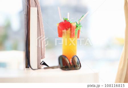 Sunglasses lying near alcoholic cocktail glass on beach closeup 108116815