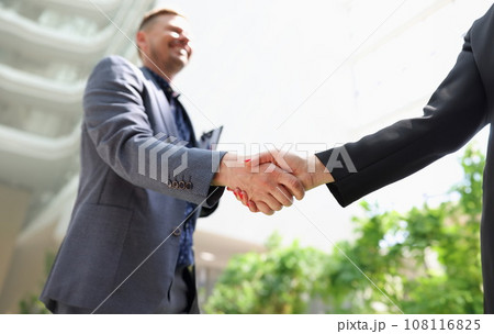 Business man and woman in suits shaking hands closeup Business man and woman in suits shaking hands closeup 108116825