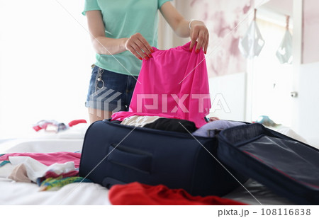 Female hand putting dress in suitcase in bedroom closeup Female hand putting dress in suitcase in bedroom closeup 108116838