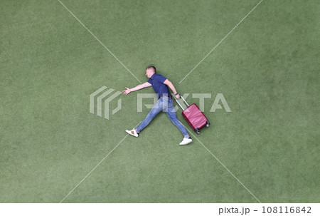 Young man with suitcase walking on green grass top view Young man with suitcase walking on green grass top view 108116842