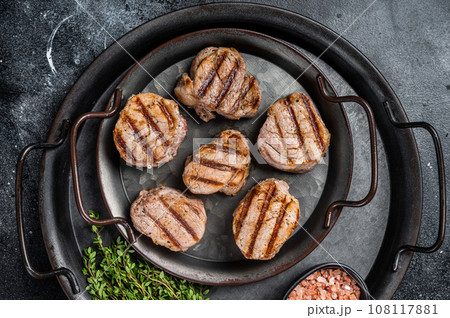 Roasted pork medallions steaks, tenderloin meat. Black background. Top view Roasted pork medallions steaks, tenderloin meat. Black background. Top view 108117881