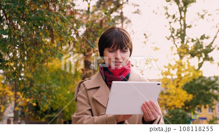 Woman prepares presentation on tablet for meeting with investor in park 108118255