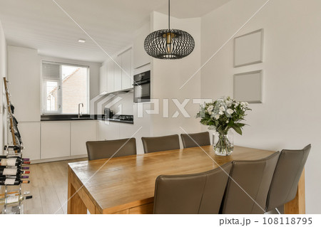 a dining room with wooden table and chairs in the middle of the room, there is a vase of flowers on the table a dining room with wooden table and chairs in the middle of the room, there is a vase of flowers on the table 108118795