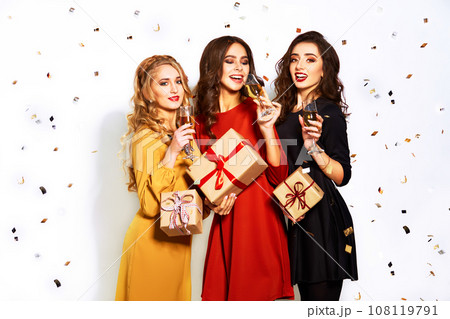 portrait of three happy young women in santa claus hat with gift and sparklers .Christmas concept. 108119791