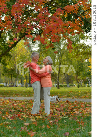 Elderly couple dance in the park in autumn. 108120018