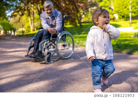 Dad on wheelchair playing with his little son in the park Dad on wheelchair playing with his little son in the park 108121953
