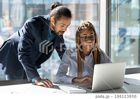 Confident African American mentor businessman training new employee using laptop Confident African American mentor businessman training new employee using laptop 108123930