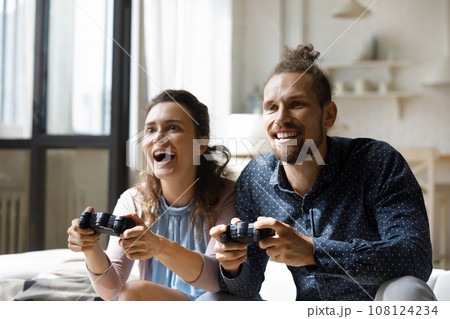 Cheerful excited young couple playing virtual video games Cheerful excited young couple playing virtual video games 108124234