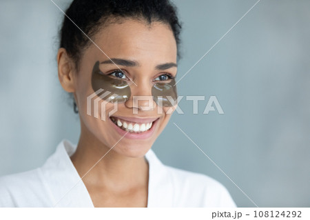 Smiling biracial woman use under eye gel patches 108124292
