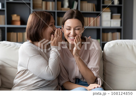 Elderly mother telling on ear to adult daughter a secret 108124850