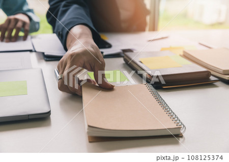 Close up shot of hands of man picking up notebook in office. 108125374