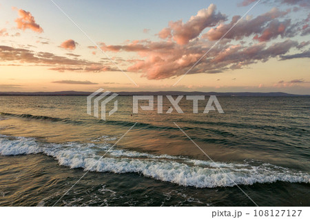 Sea surface with blue water waves under yellow and purple sunset sky. 108127127