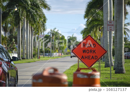 Road work ahead sign on street site as warning to cars about construction and utility works Road work ahead sign on street site as warning to cars about construction and utility works 108127137