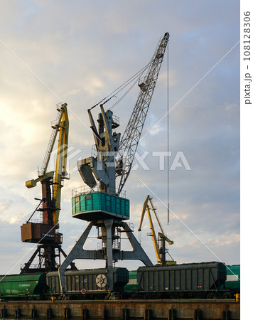 Harbor cranes with grain wagons between crane legs, seaport industry scene, grain export 108128306