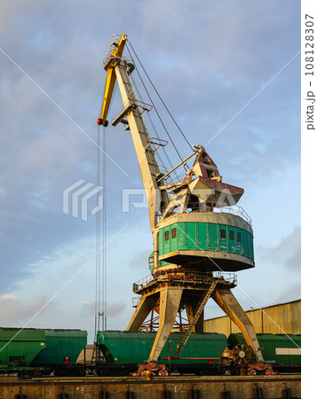 Harbor crane with grain wagons between crane legs, seaport industry scene, grain export 108128307
