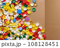 Used PET recycling plastic bottle cap plastic lids. Colorful bottle caps background cardboard box. Garbage PET waste recycling bottle cap sorting waste plastic garbage collection. Recyclable materials 108128451
