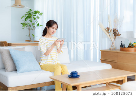 部屋でスマホを操作する若い女性 部屋でスマホを操作する若い女性 108128672