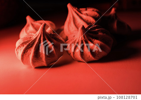 Four meringue cookies in red light on a dark background. Four meringue cookies in red light on a dark background. 108128701
