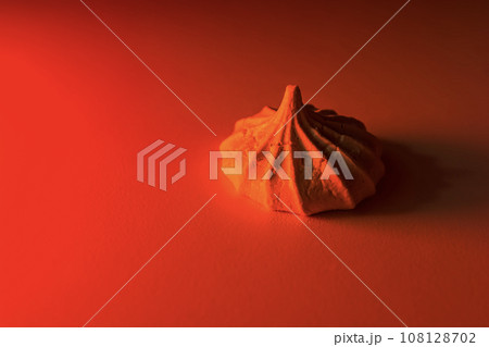One meringue cookie in red light on a light background. 108128702