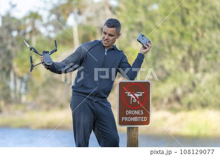 Operator is disappointed because he can not fly his quadcopter in national park no drone area. Man is unable to use his UAV near restriction notice sign 108129077
