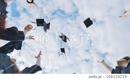 Joyful graduates stand in a circle and toss their caps up. 108129219