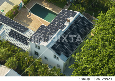 Expensive american residential house with rooftop covered with solar photovoltaic panels for producing of clean ecological electrical energy in suburban rural area. Concept of autonomous home 108129924