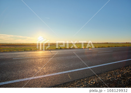 Empty intercity road with asphalt surface and white markings in evening 108129932