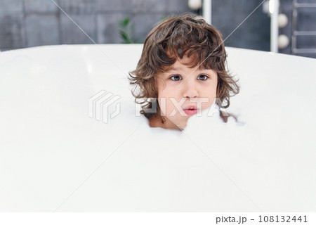 Funny little boy plays with foam in a bath. 108132441