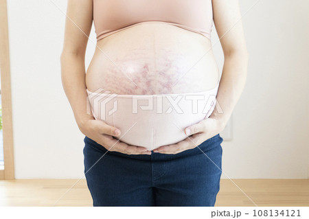 臨月の妊婦女性のお腹と腹帯 108134121