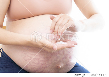 妊娠線ができたお腹にクリームを塗る女性の手と臨月のお腹 妊娠線ができたお腹にクリームを塗る女性の手と臨月のお腹 108134142