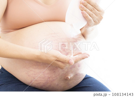 妊娠線ができたお腹にクリームを塗る女性の手と臨月のお腹 妊娠線ができたお腹にクリームを塗る女性の手と臨月のお腹 108134143