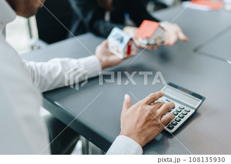 Guarantee, mortgage, contract, contract, signed, real estate agent or bank officer holding a calculator, submits a bid with a customer to buy a home before signing to make a deal. 108135930