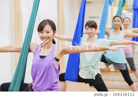 スポーツジムでエアリアルヨガをする若い女性 スポーツジムでエアリアルヨガをする若い女性 108136111