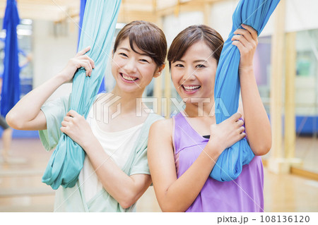 スポーツジムでエアリアルヨガをする若い女性 スポーツジムでエアリアルヨガをする若い女性 108136120