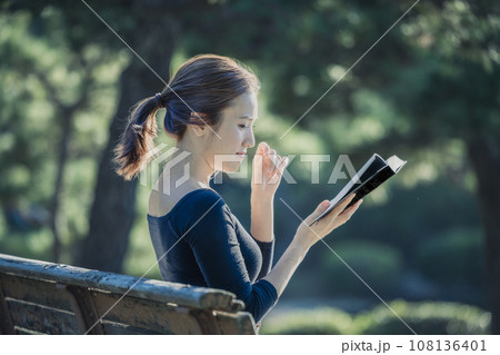 公園のベンチで本を読む女性 108136401