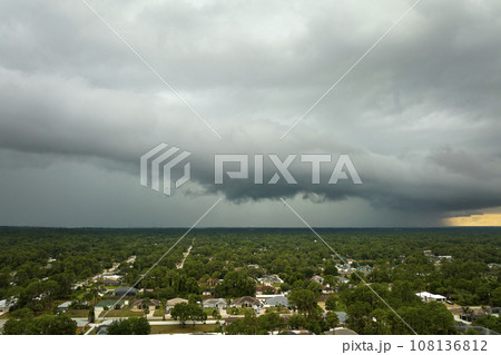 Dark stormy clouds forming on gloomy sky before heavy rainfall over suburban town area Dark stormy clouds forming on gloomy sky before heavy rainfall over suburban town area 108136812