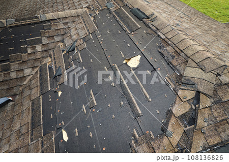 Damaged house roof with missing shingles after hurricane Ian in Florida. Consequences of natural disaster Damaged house roof with missing shingles after hurricane Ian in Florida. Consequences of natural disaster 108136826