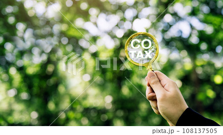 Hand holding magnifying glass with CO2 reduction icon inside. carbon credit to limit global warming from A climate-neutral long-term strategy greenhouse gas emissions targets. 108137505
