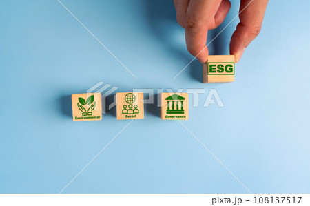 Hand holds wooden cubes with abbreviation ESG. ESG concept of environmental, social and governance. Sustainable corporation development. 108137517