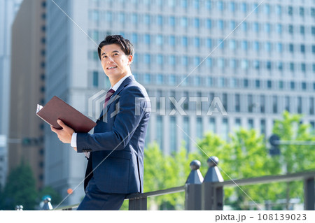 オフィス街でスマホを見るミドルのビジネスマン 108139023
