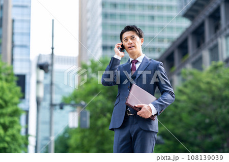 オフィス街でスマホを使うミドルのビジネスマン 108139039