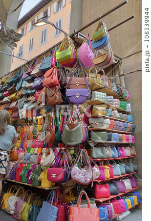 Colorful leather purses, handbags, wallets and handbags are displayed by street vendors at the outdoor Lorenzo Market at Florence, Italy. 108139944
