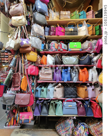 Colorful leather purses, handbags, wallets and handbags are displayed by street vendors at the outdoor Lorenzo Market at Florence, Italy. 108139945