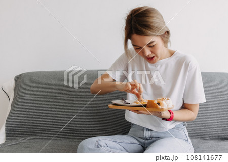 Woman in white t-shirt eating her own homemade breakfast. 108141677