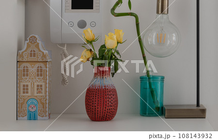 Yellow roses in Red ceramic vase, Lucky bamboo, Intercom handset / Door entry, Light bulb and tin music box. Home decor, Yellow roses in Red ceramic vase, Lucky bamboo, Intercom handset / Door entry, Light bulb and tin music box. Home decor, 108143932