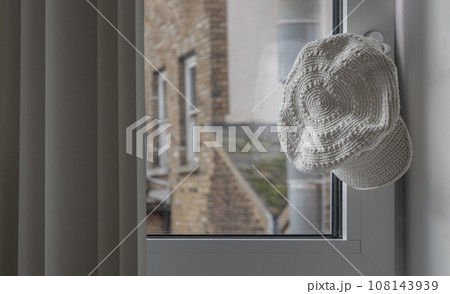White cotton crochet hat hung on the glass window handle. 108143939