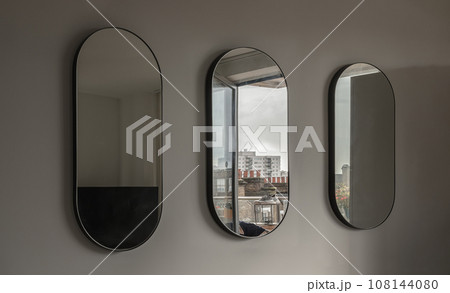 View of Three Capsula pill shaped mirror on white wall. View of Three Capsula pill shaped mirror on white wall. 108144080
