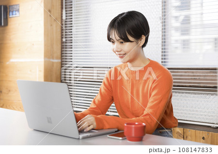 ノートパソコンで仕事している笑顔の20代ショートカットの女性 108147833